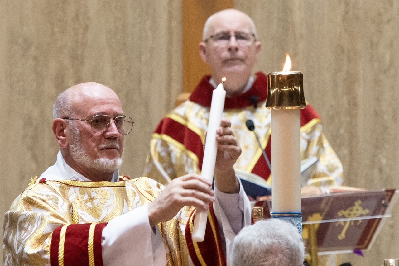 Easter 2023 - Monsignor Zimmer watching as Deacon Popik lights candle from the Easter candle