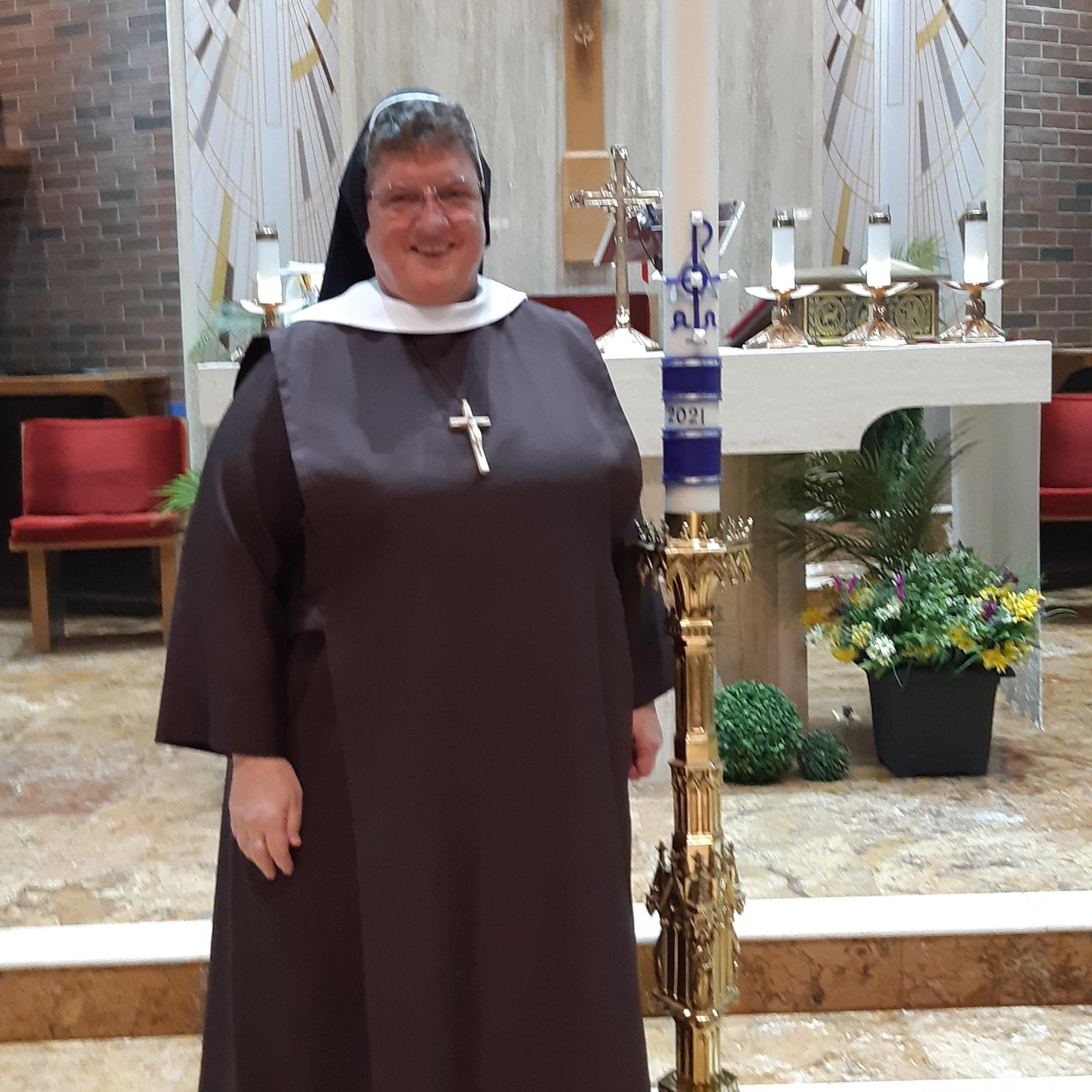 Sr. Christina in front of altar beside 2021 Easter candle