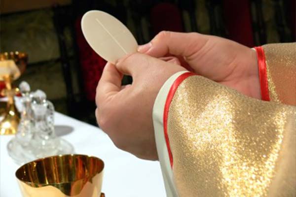 Priest Hands Holding Communion over alter